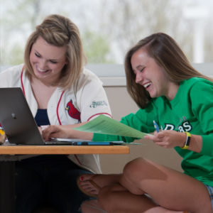 两位女孩在笔记本电脑前笑